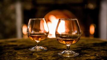 Two wine glasses on a table with a blurred background of a fireplace.