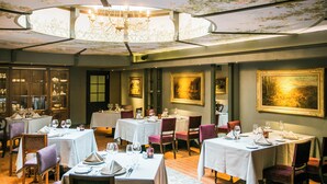 A dining area with multiple tables set for service, a chandelier, and framed artwork on the walls. -  Antonius Boutique Hotel (Tartu)