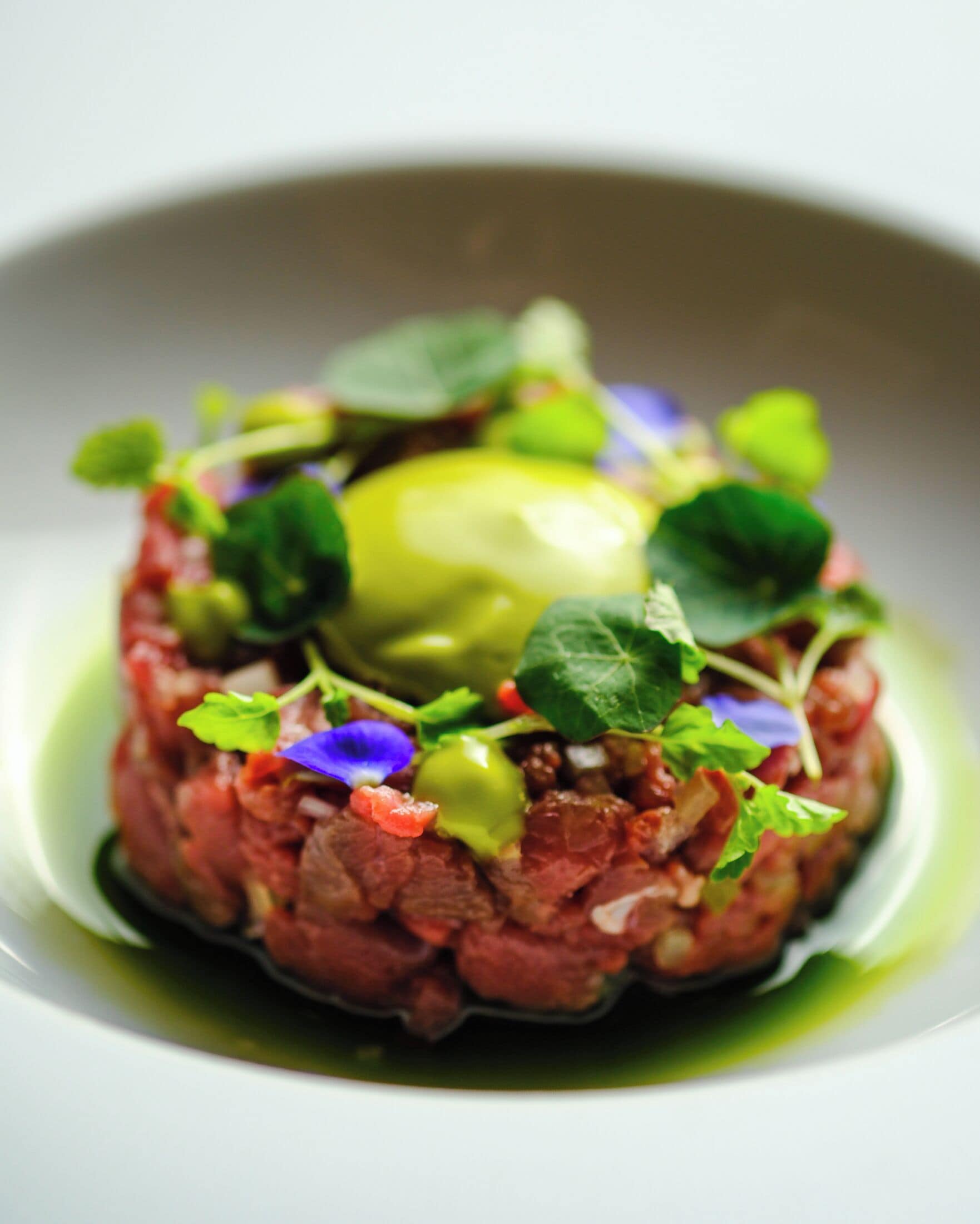 A dish with a central spherical element surrounded by greens and other ingredients.