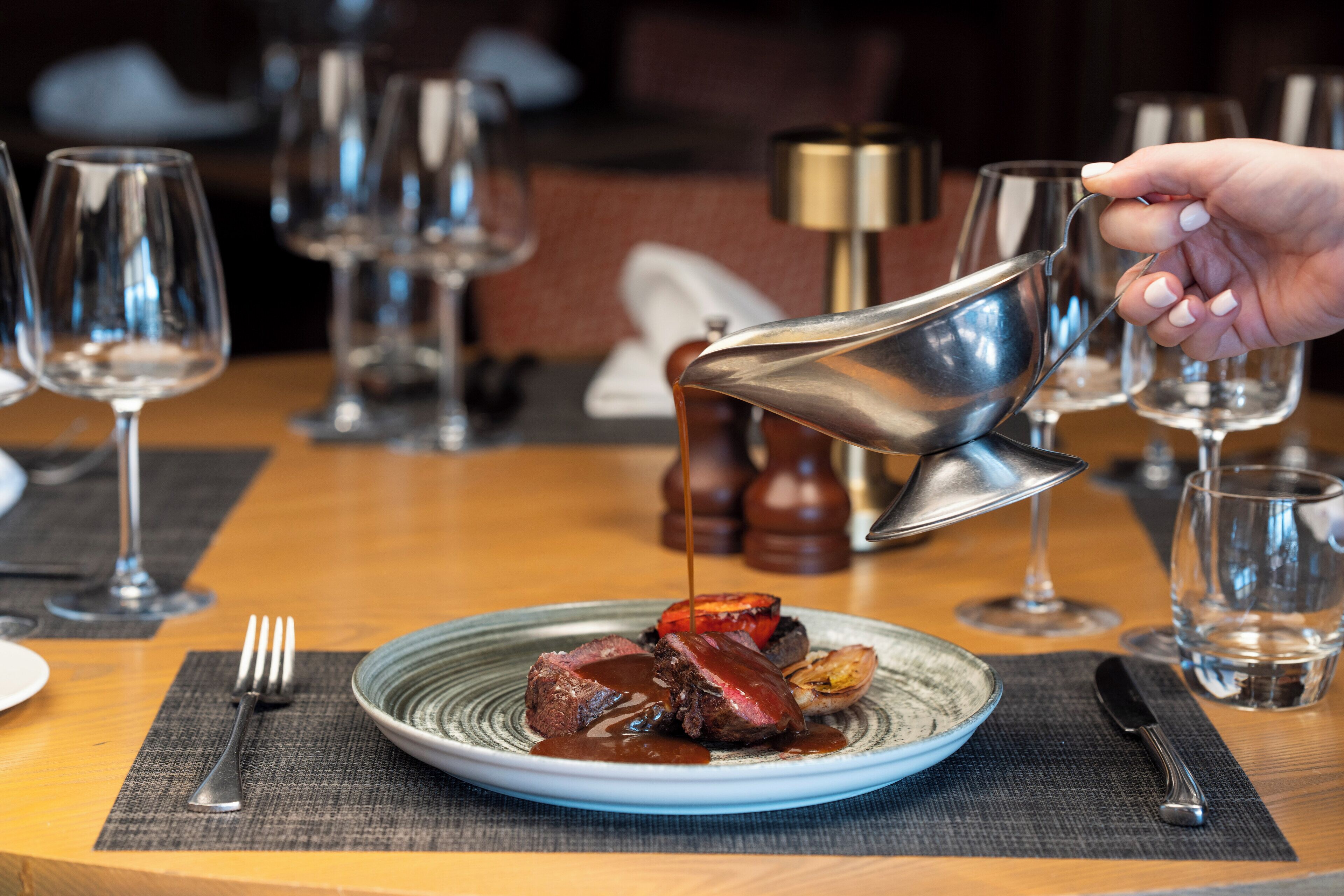 Una mesa de comedor con un plato de comida, un tenedor y un cuchillo.