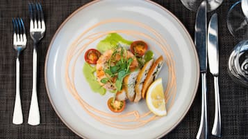 Prato de comida com salada, camarão e limão sobre um prato branco com linhas laranja.
