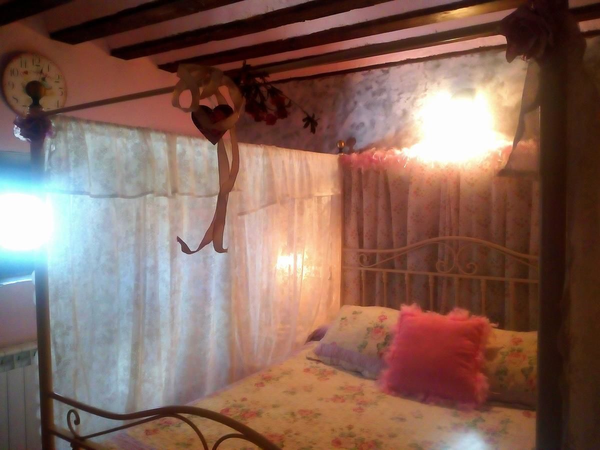 A bedroom with a bed, a clock, and a hanging heart-shaped decoration.