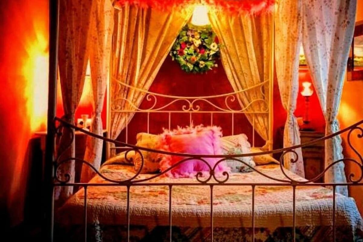 A cozy room with a bed, curtains, and a floral decoration.