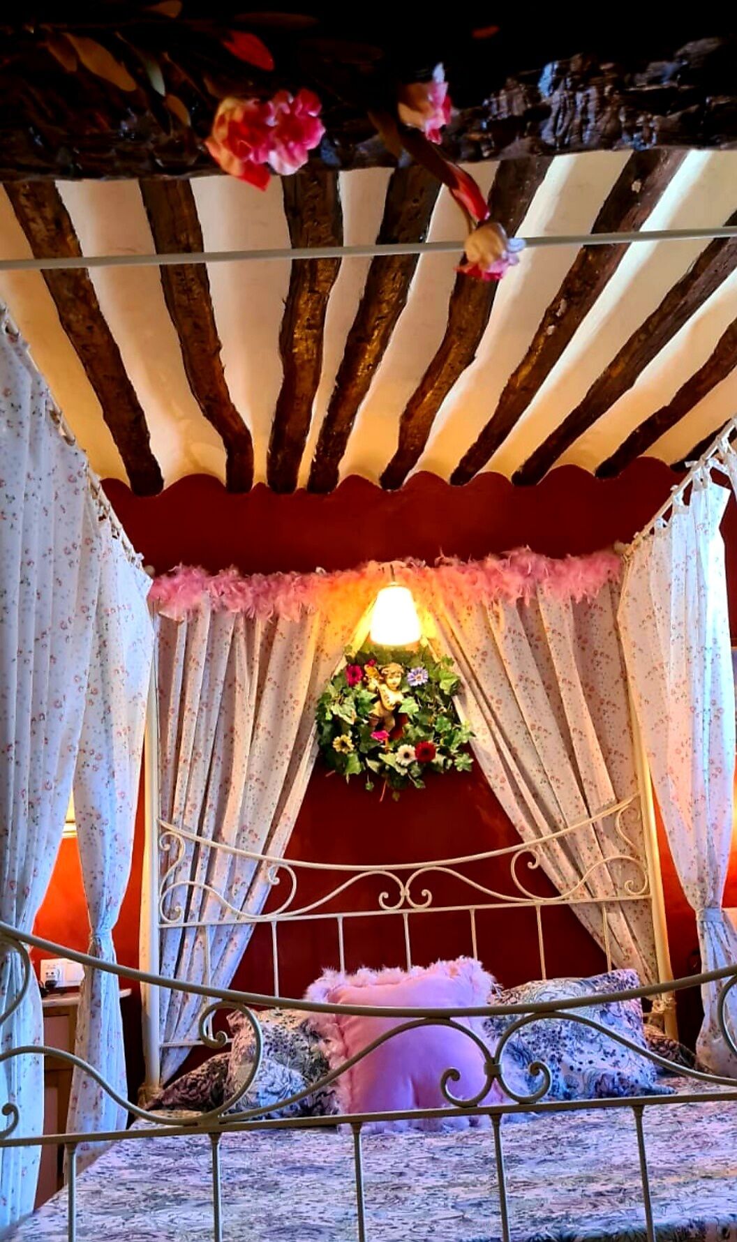 Een gezellige kamer met een bed, bloemen gordijnen en een decoratief plafond.