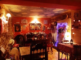 Un comedor acogedor con una mesa y sillas de madera, un techo de diseño único y diversas decoraciones, incluyendo luces colgantes y cuadros enmarcados.