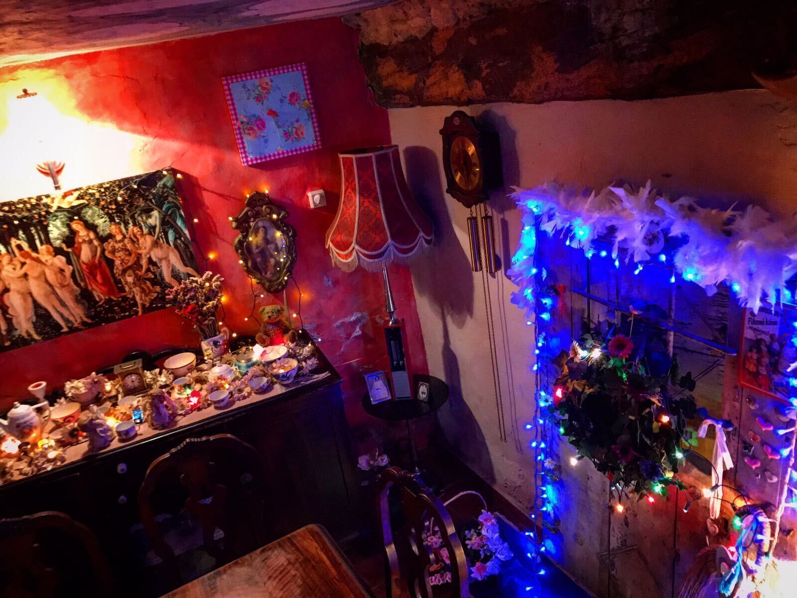 Una habitación con pared roja, un cuadro, un reloj y una mesa con diversos objetos y luces azules.