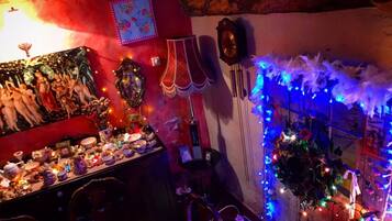 Una habitación con pared roja, un cuadro, un reloj y una mesa con diversos objetos y luces azules.