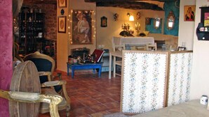 Un salon chaleureux au décor rustique, avec une chaise en bois, une table bleue et un paravent à motifs.