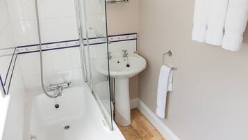 A bathroom with a glass-enclosed shower, a white sink, and a mirror above the sink.