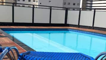 Piscina com um deck de madeira e uma cadeira azul.