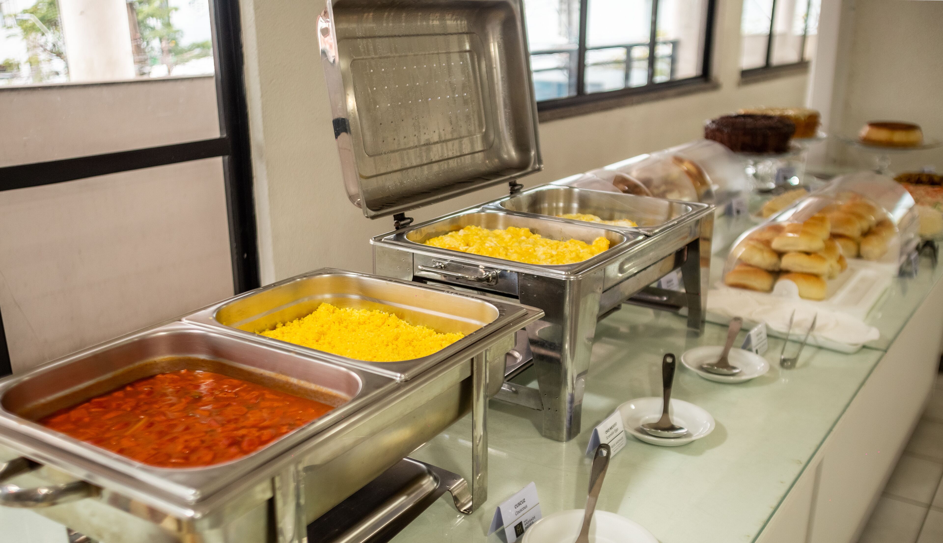 Un buffet proposant une variété de plats, notamment des œufs brouillés, des pâtes et du pain.