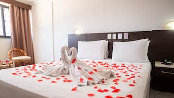 A hotel room with a neatly made bed, a chair, and a bedside table.