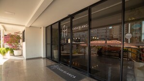 Een hotelentree met een glazen gevel, een potplant en een deurmat met de naam van het hotel.