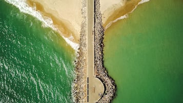 Vista aérea de una playa con un paseo marítimo pavimentado a lo largo de la costa.