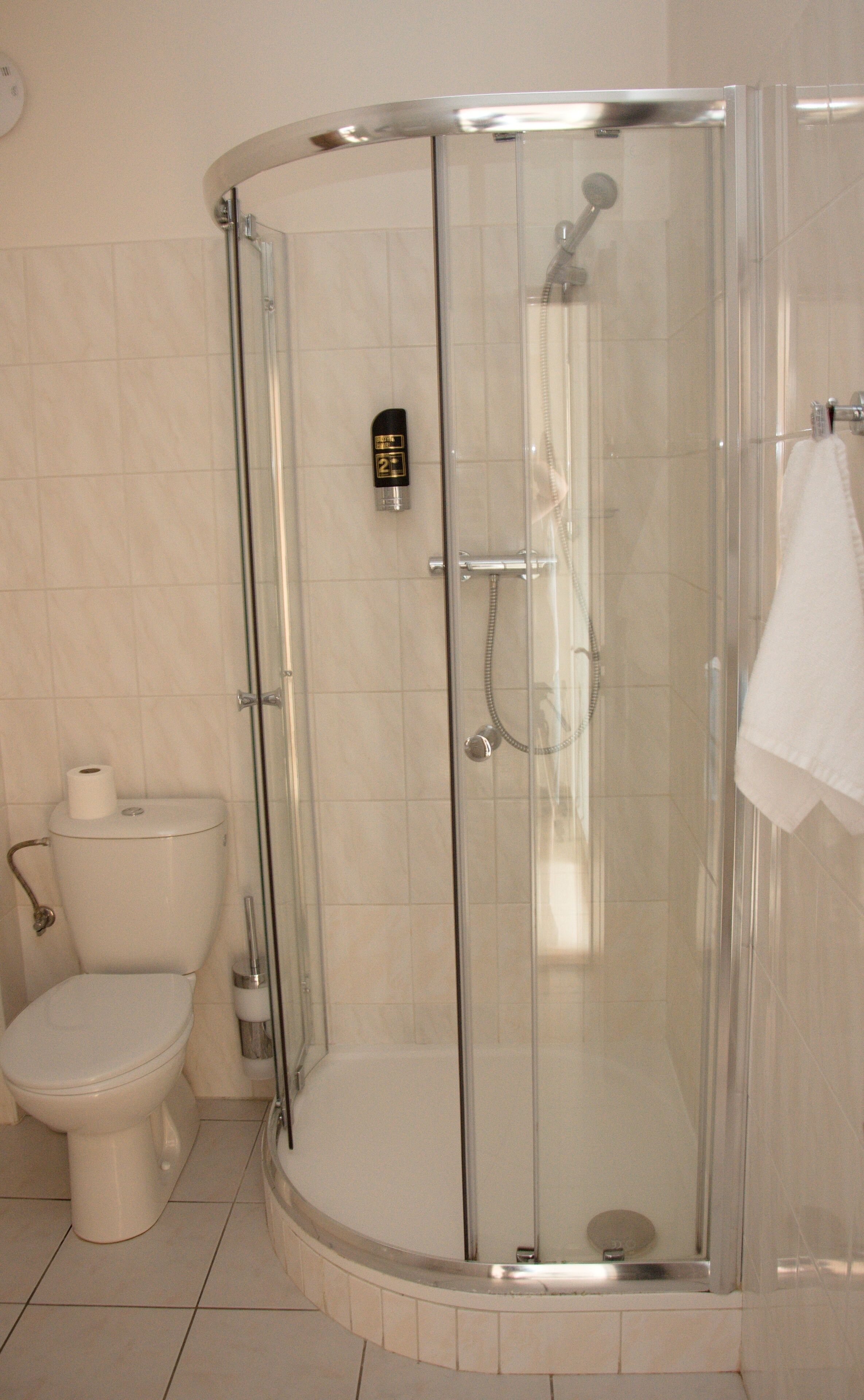 Een badkamer met een douche met glazen wand, een toilet en een handdoek aan de muur.