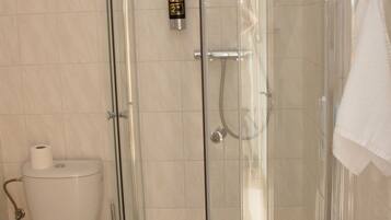 Een badkamer met een douche met glazen wand, een toilet en een handdoek aan de muur.