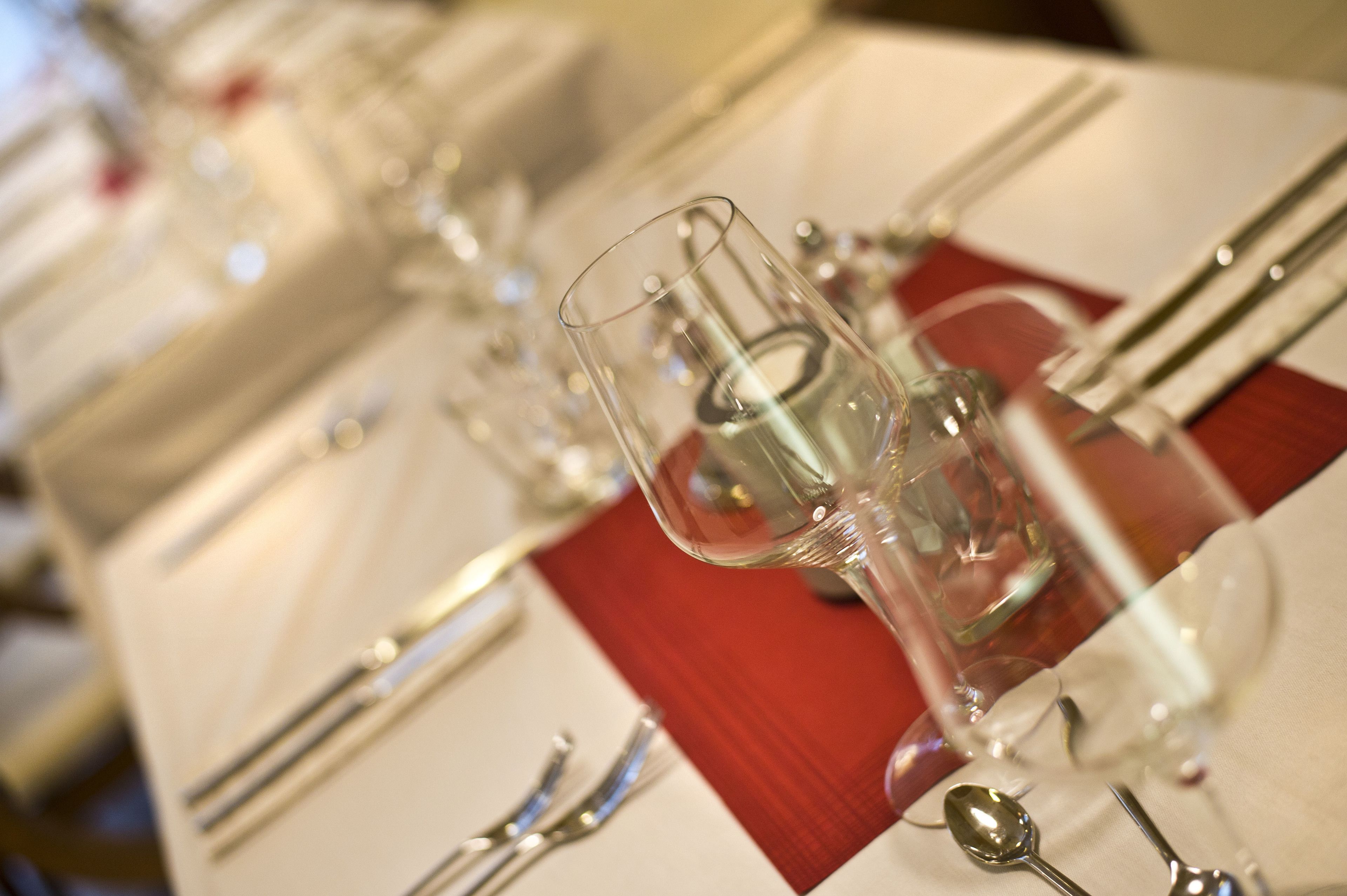 A table set with clear glassware, silverware, and a red napkin.