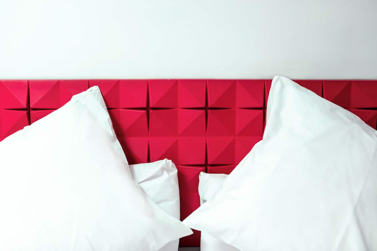 A bed with a red headboard and white pillows.