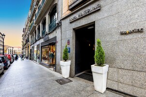 L’entrée d’un hôtel, avec une façade en pierre, une enseigne indiquant « Hôtel Mayerling » et deux plantes en pot.