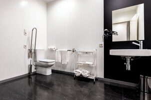 Une salle de bain moderne équipée d’un WC, d’un lavabo, d’un miroir et d’un porte-serviettes.