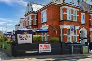 A brick building with a sign for Revado's Kitchen, indicating an outdoor dining area. - Revado Hotel, Norwich City Centre (Norwich)