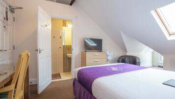 A bedroom with a bed, a television, a desk, and a chair.