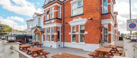 A hotel with a traditional facade, outdoor seating, and a clear sky.