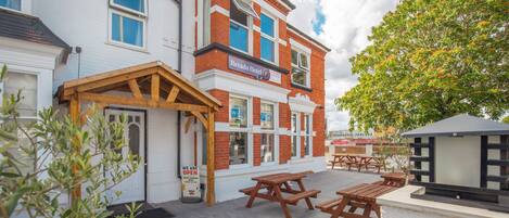 A hotel with a patio area featuring wooden tables and benches.