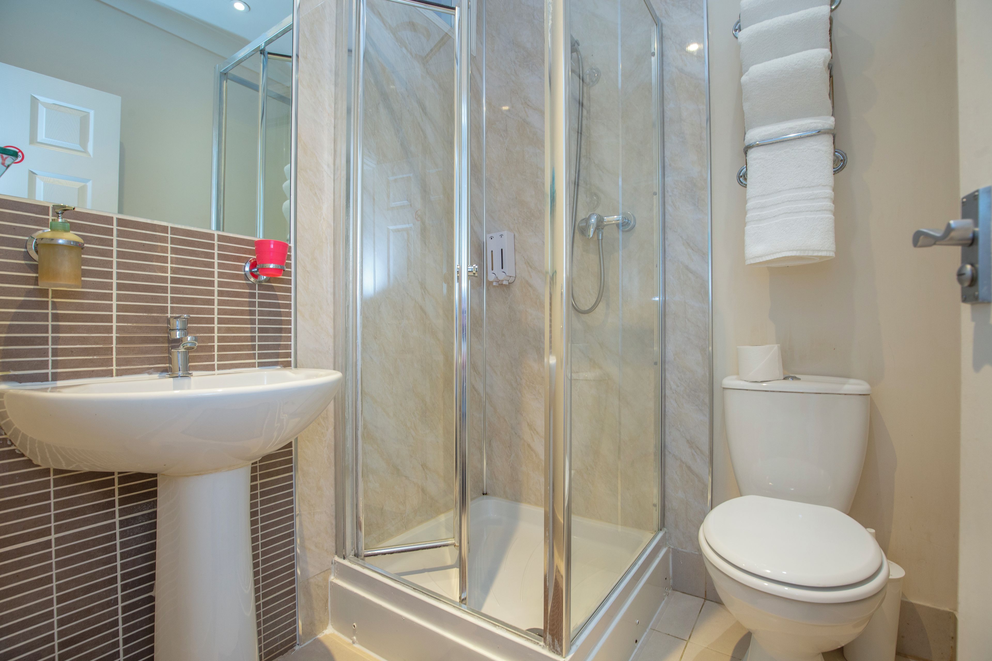 Un baño con ducha acristalada, lavamanos e inodoro.