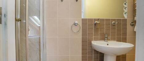 Un baño con ducha, lavabo y espejo.
