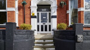 A two-story brick building with a white-framed entrance and a black door. There are two black stone pillars at the entrance, and a small set of steps leading up to the door. - Revado Hotel, Norwich City Centre (Norwich)