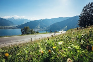 Une route bordée de cyclistes, un lac et des montagnes en arriÚre-plan.
