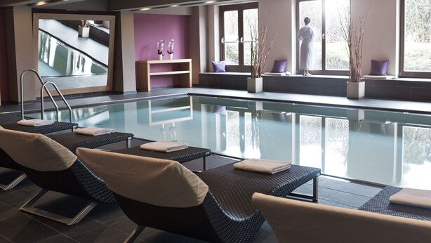 A spa area with a pool, reclining chairs, a mirror, and a view of the outdoors. - POP-UP LIVING Zell am See (Zell am See)