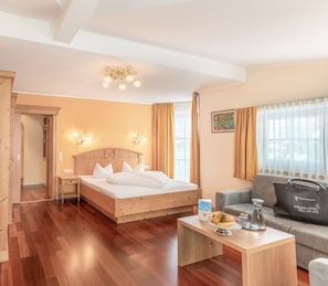 Une chambre dâhĂŽtel avec un lit en bois, un canapĂ©, une table basse et une vue sur lâextĂ©rieur.