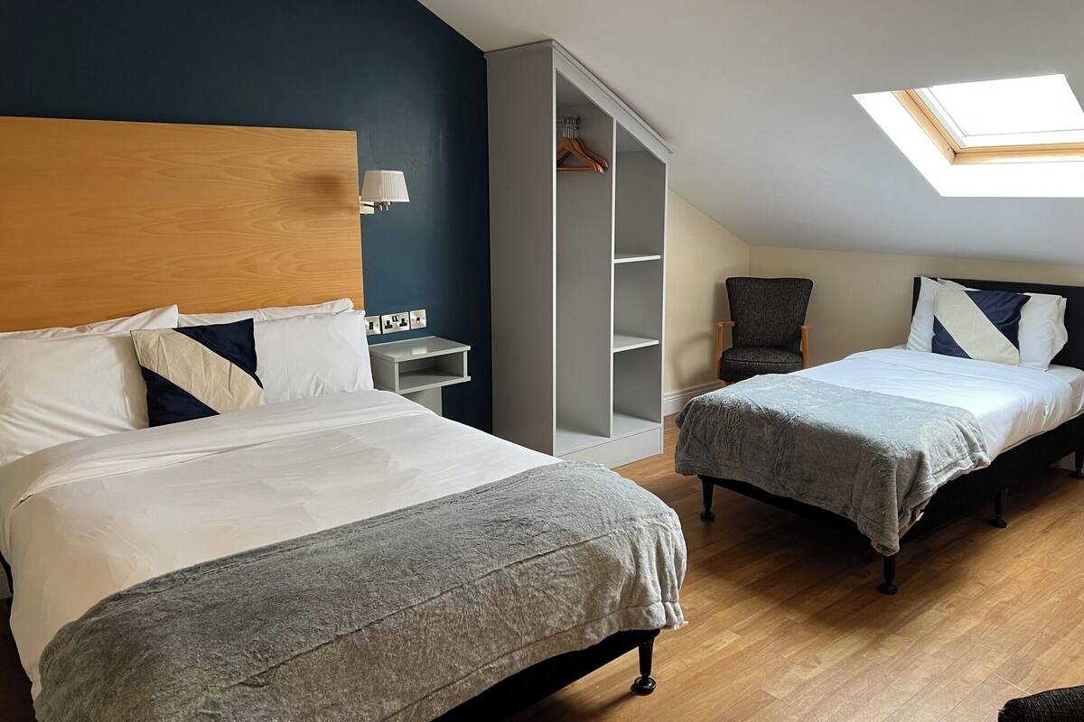 Ett hotellrum med två sängar, en garderob, en stol och ett takfönster.