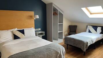 Habitación de hotel con dos camas, un armario, una silla y un tragaluz.