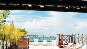 A rooftop terrace with lounge chairs and a view of the sea. - Maritima Flat (Natal)