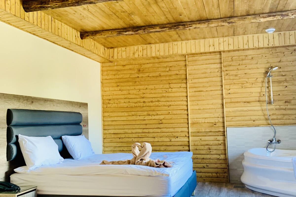 Ein Schlafzimmer mit Bett, Nachttisch und Badewanne.