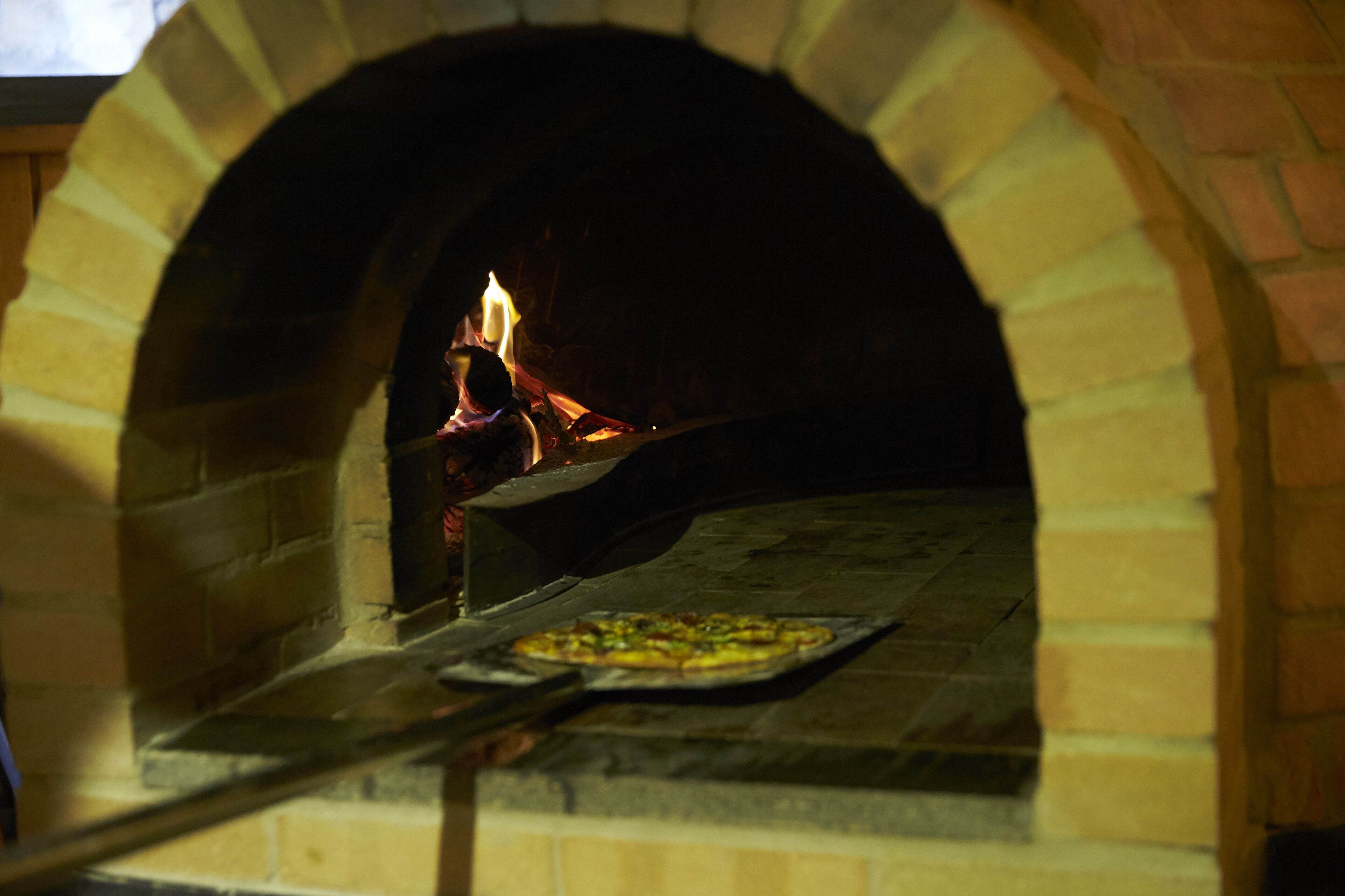 Un horno de ladrillo con una pizza en su interior.