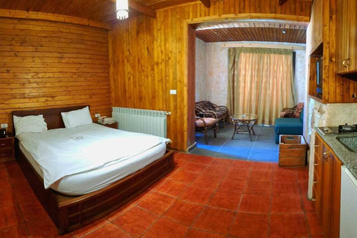 Ein holzgetäfeltes Zimmer im Chalet-Stil mit einem Bett, einem kleinen Tisch und einer Küchenzeile.