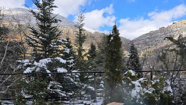 A pool with a wooden deck, surrounded by snow-covered trees and mountains in the background. - Faraya Village Club (Faraya)