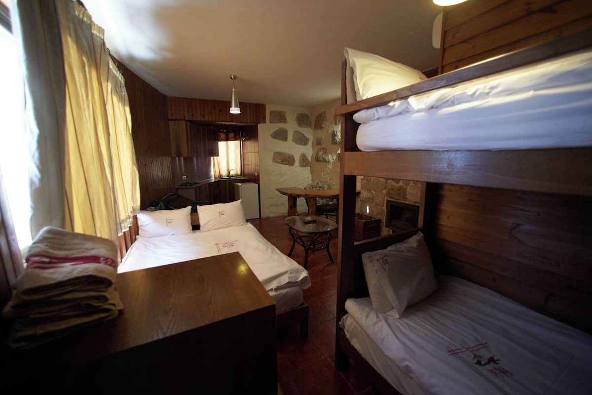 Ein gemütliches Zimmer mit einem Etagenbett, einem Holztisch, einem kleinen Tisch und einer Steinwand.