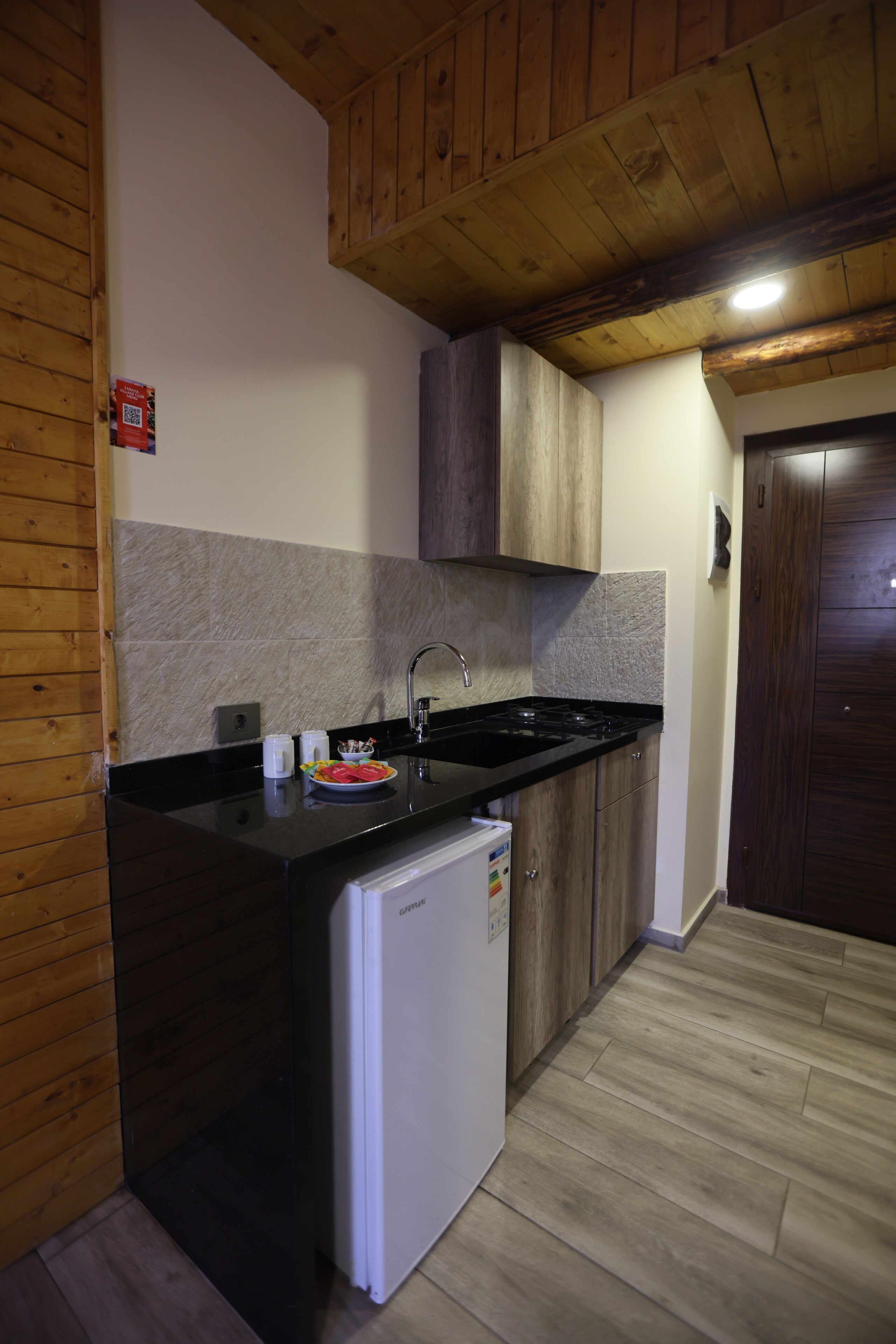 A compact kitchen with wooden cabinetry, a white refrigerator, and a black countertop.