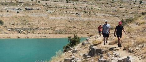 Un sendero rocoso que lleva a un cuerpo de agua, con un paisaje montañoso al fondo.