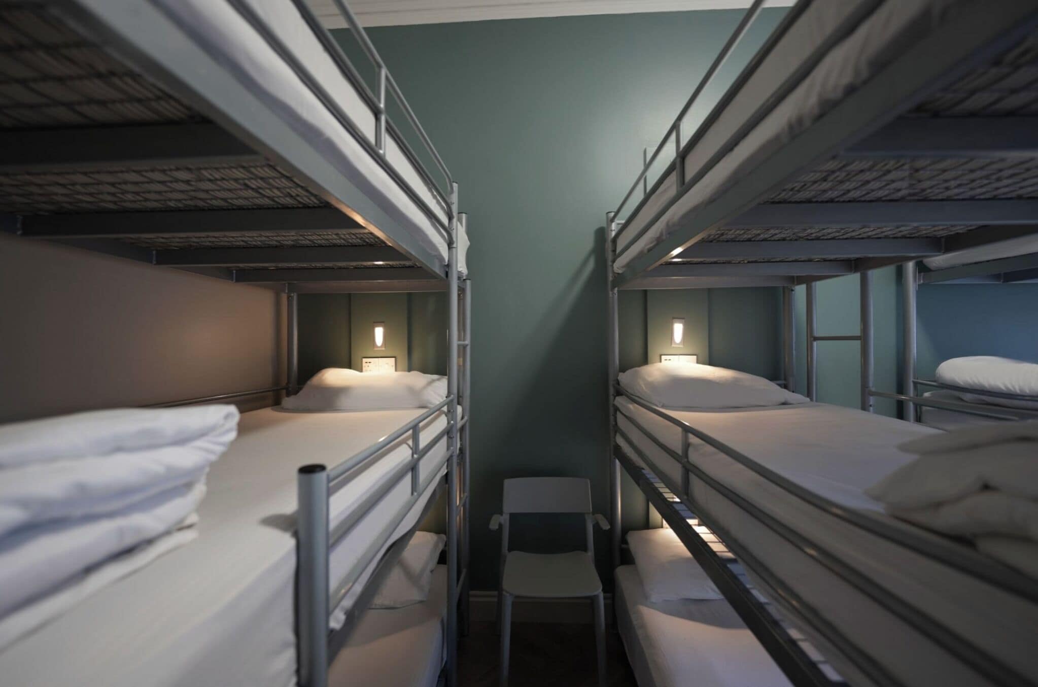 A bunk room with metal bunk beds, a small chair, and bedside lamps.