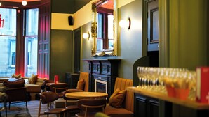 A cozy interior with a fireplace, seating area, and a bar with glasses. - Revolver Edinburgh (Edinburgh)