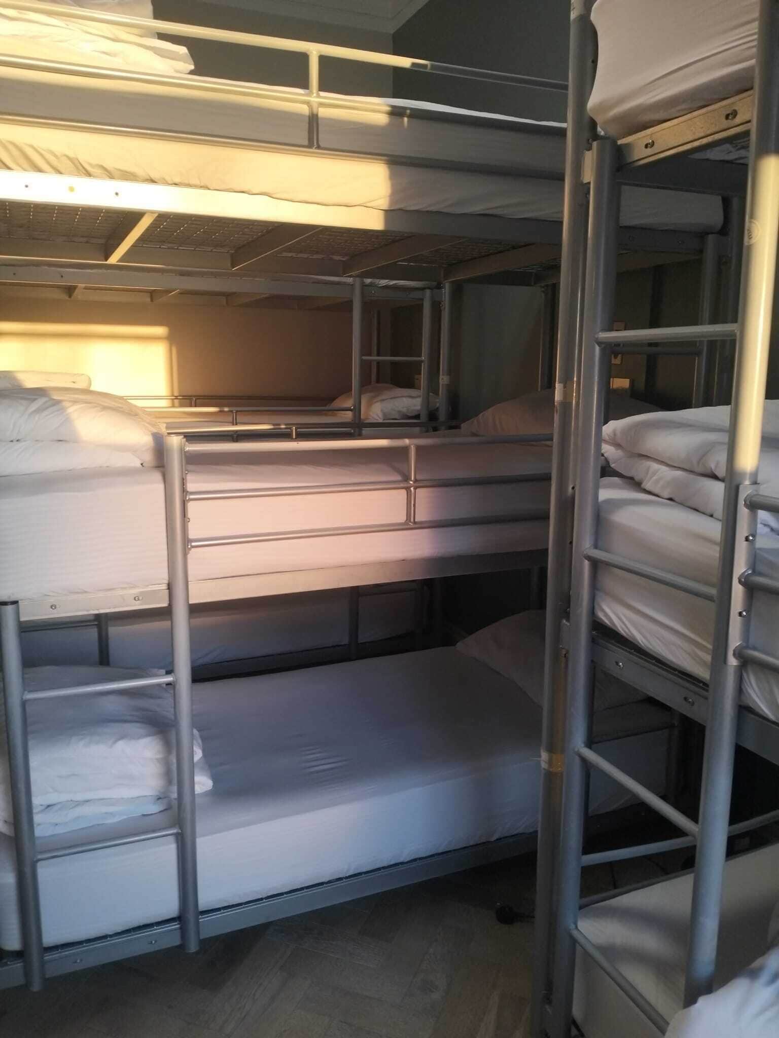 A bunk bed room with metal railings and white bedding.