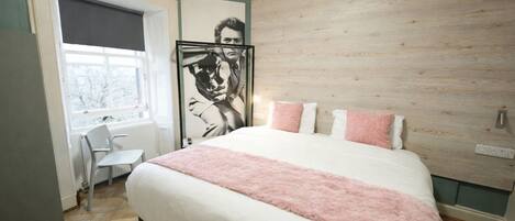 A bedroom with a large bed, a desk, and a window.