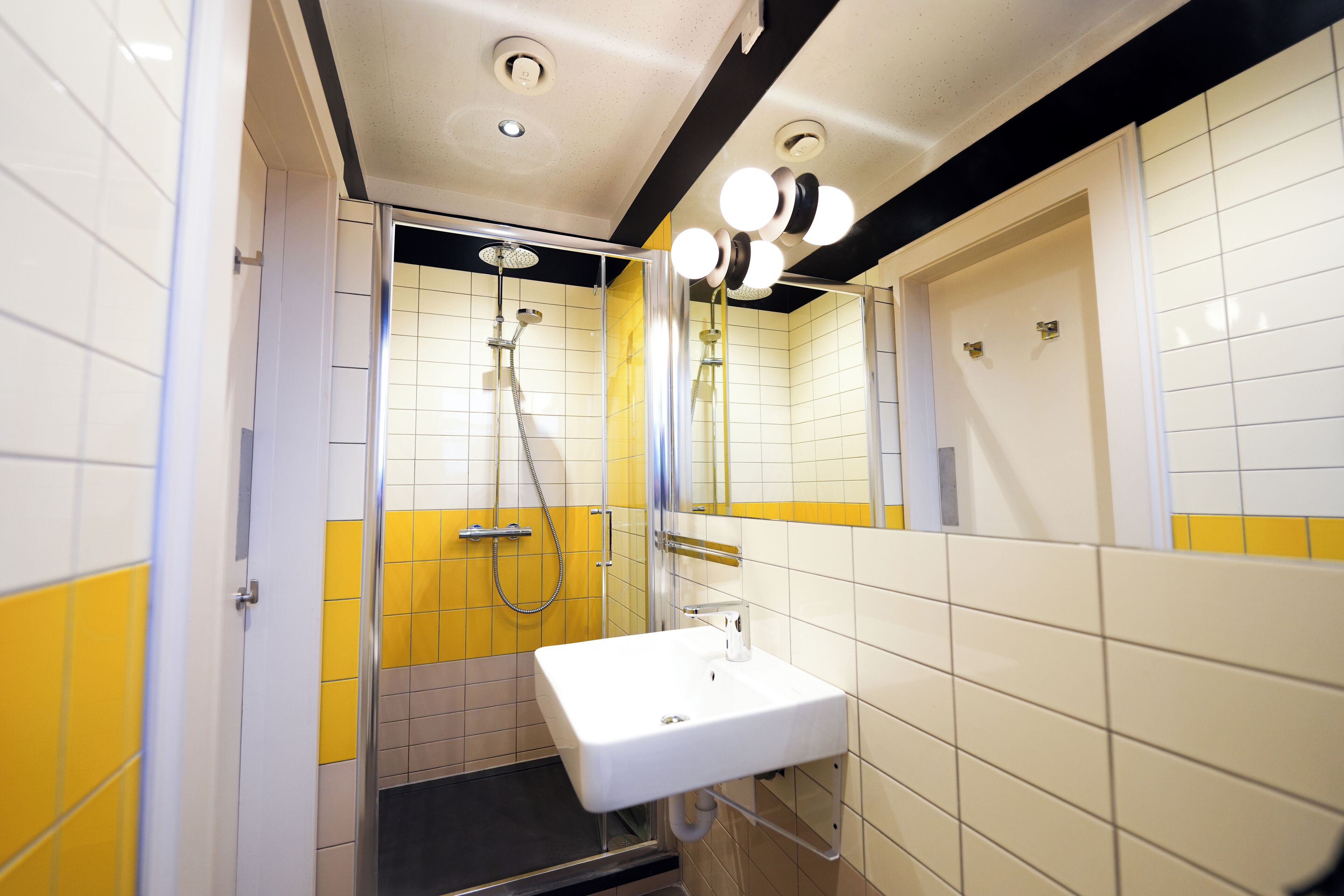 Een badkamer met een douche, wastafel en spiegel.