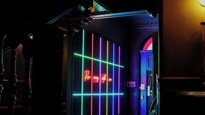 A neon-lit hallway with a 'Ray of Light' sign, a round table, and a staircase. - Revolver Edinburgh (Edinburgh)
